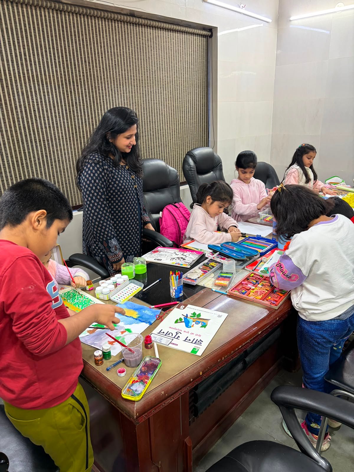Girls working on their artwork with crayons and watercolours under Priyanka Gupta's guidance